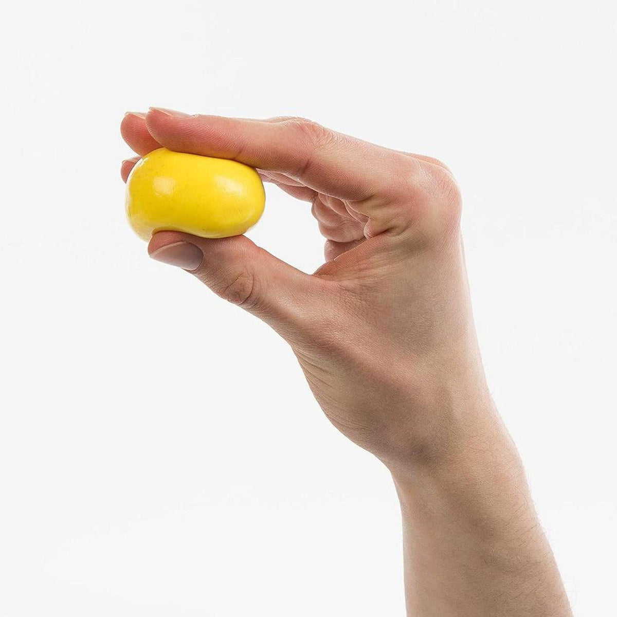 Hand squeezing a smooth, bright yellow ball of non-toxic therapy putty for hand strength and dexterity exercises.