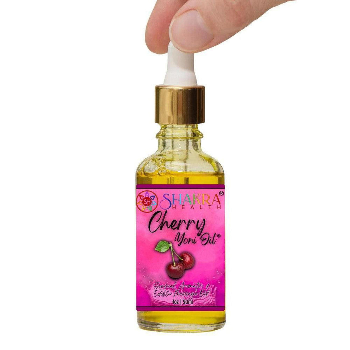 Hand holding a 30ml glass dropper bottle of Shakra Health cherry yoni oil with a pink label and gold cap.