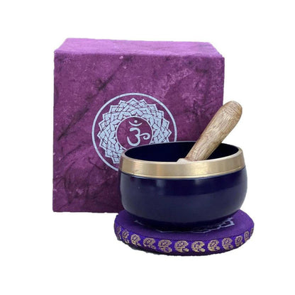 Deep purple singing bowl with a wooden striker, matching cushion, and gift box featuring a white Om symbol design.