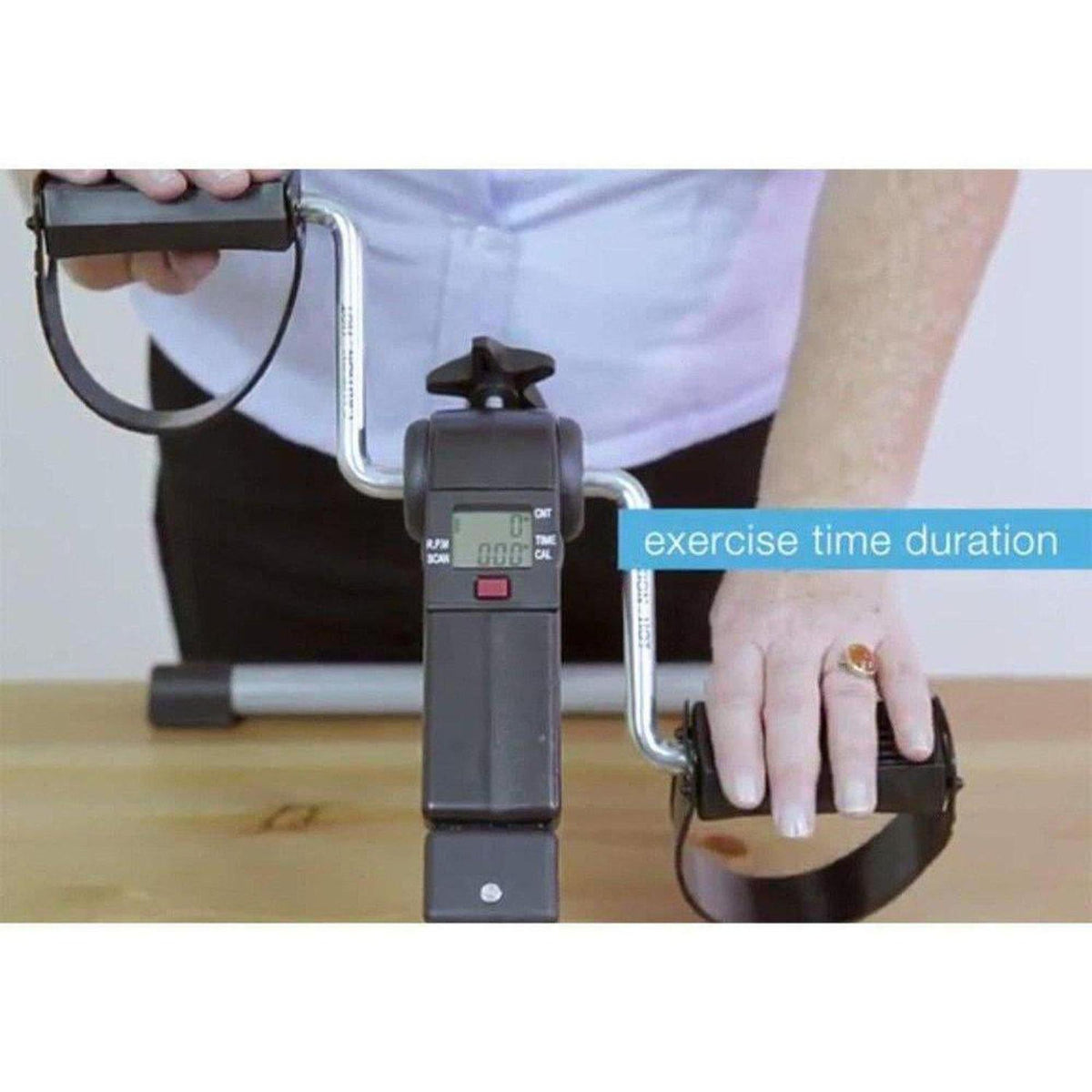 Black digital pedal exerciser on a table with a hand-operated crank and LCD screen displaying exercise time duration.
