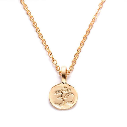 Minimalist gold necklace featuring a round pendant with an embossed Om symbol on a delicate matching chain.
