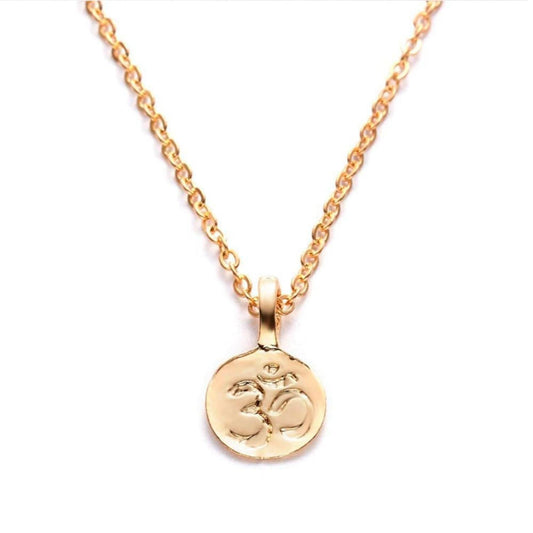 Minimalist gold necklace featuring a round pendant with an embossed Om symbol on a delicate matching chain.