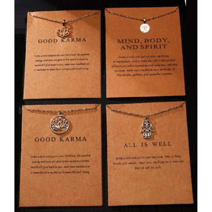 Four silver minimalist Good Karma necklaces with lotus, Om, and Hamsa charms on kraft paper mantra display cards.