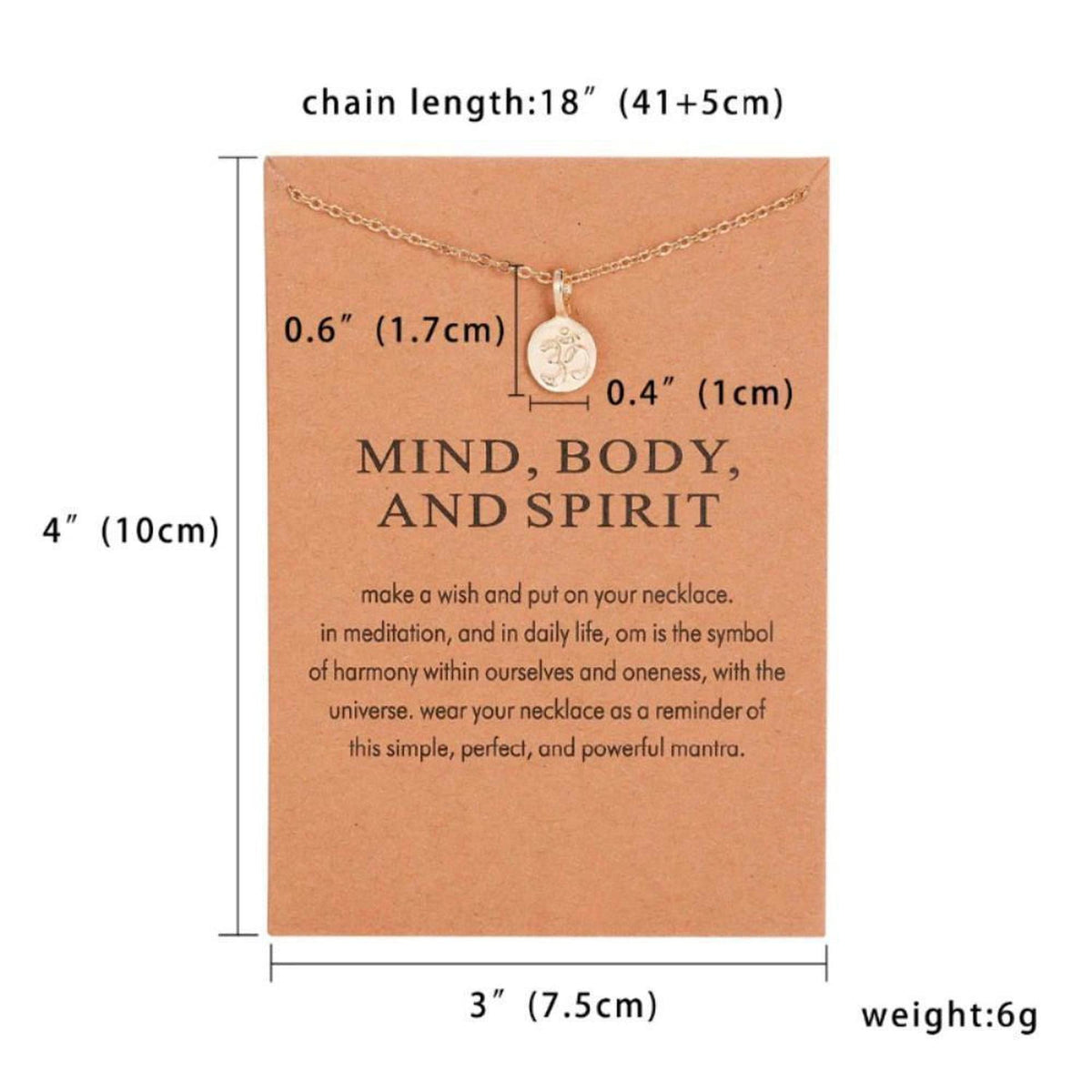 Gold Om symbol pendant necklace on a Mind, Body, and Spirit mantra display card with detailed product dimensions.