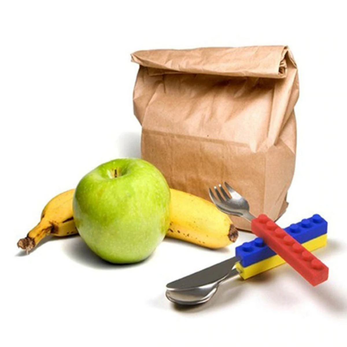 Stacking kids' cutlery set with colorful silicone building block handles, stainless steel utensils, fruit, and a lunch bag.
