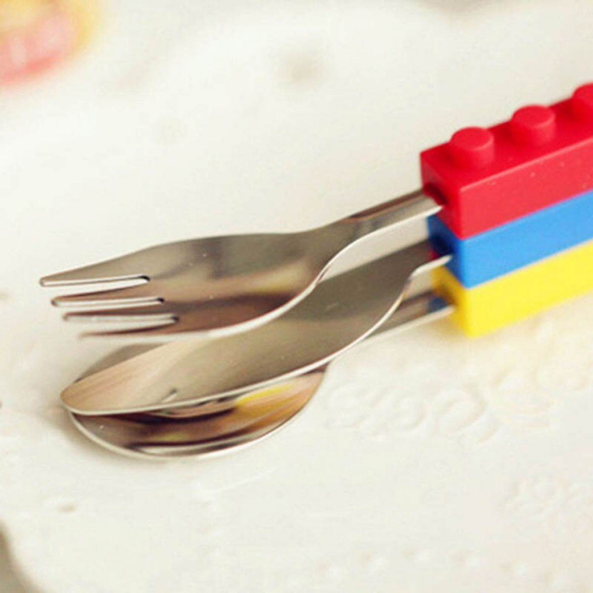 Stacking kids' cutlery set with stainless steel utensils and colorful, interlocking building block silicone handles.