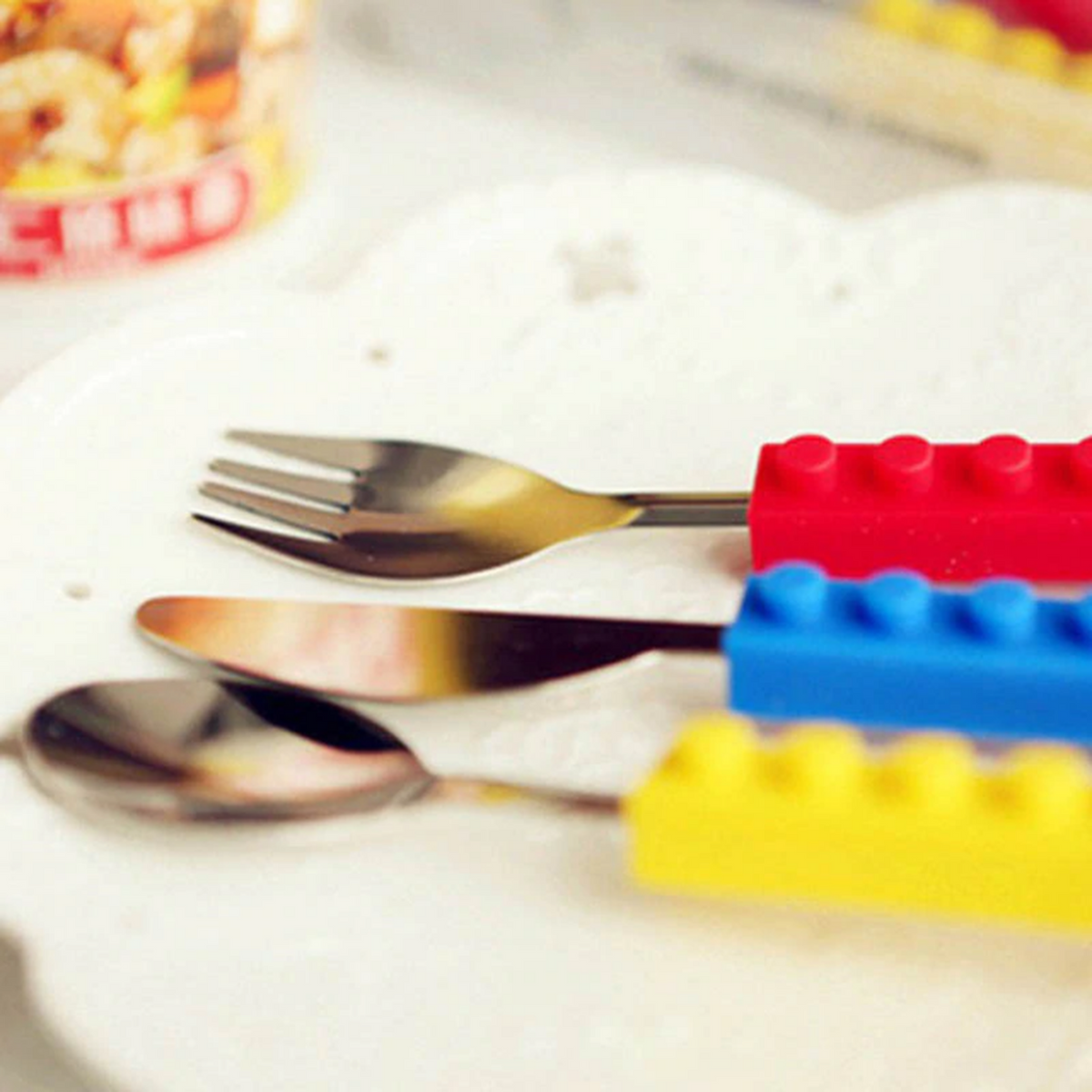 Stainless steel fork, knife, and spoon set with colorful, interlocking silicone building block handles.