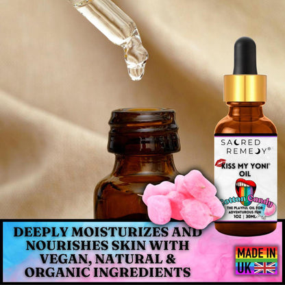 Amber glass dropper bottle of Cotton Candy Yoni Oil with pink flower petals on a soft beige fabric background.