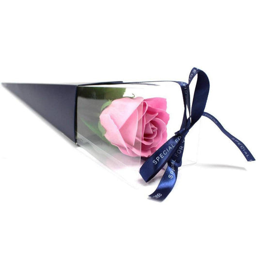 Large pink soap rose in a clear triangular gift box with a navy blue ribbon tied in a bow.