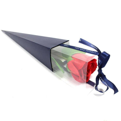 Large red soap rose in a triangular navy gift box with a clear window and a blue ribbon tied in a bow.