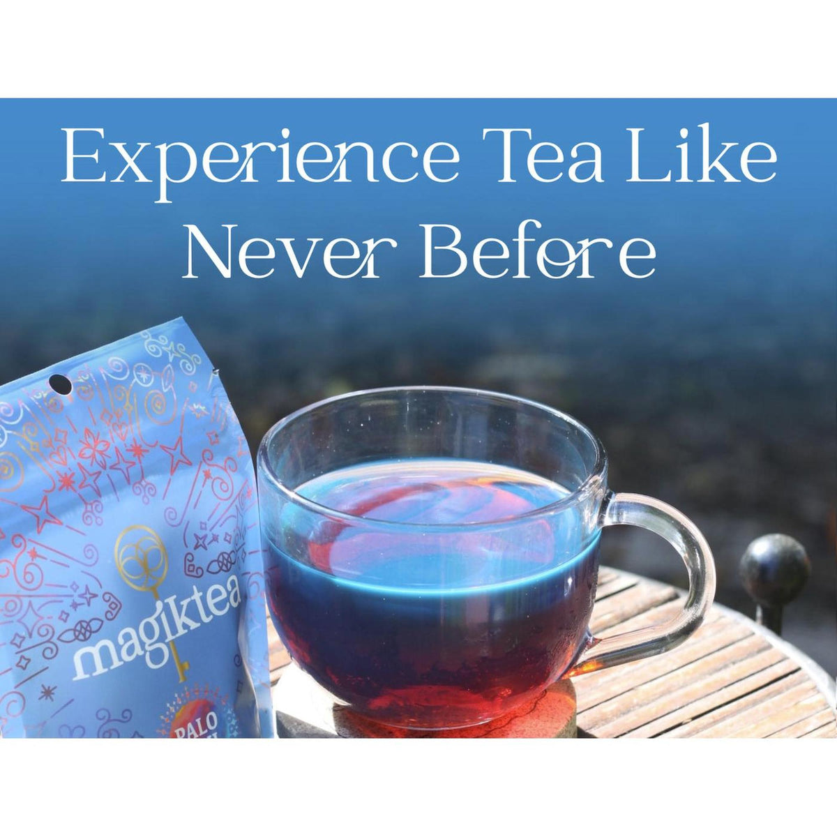 Magiktea Palo Azul pouch next to a glass cup filled with glowing, fluorescent blue herbal tea on a wooden table.