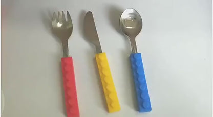 Child's stainless steel fork with easy-grip colourful silicone block handle for independent eating.