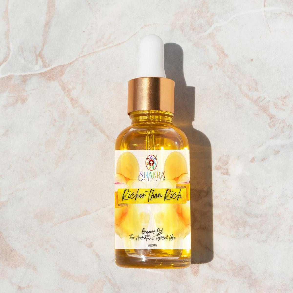 Richer Than Rich ritual oil in a 30ml glass dropper bottle with a gold cap on a marble surface.