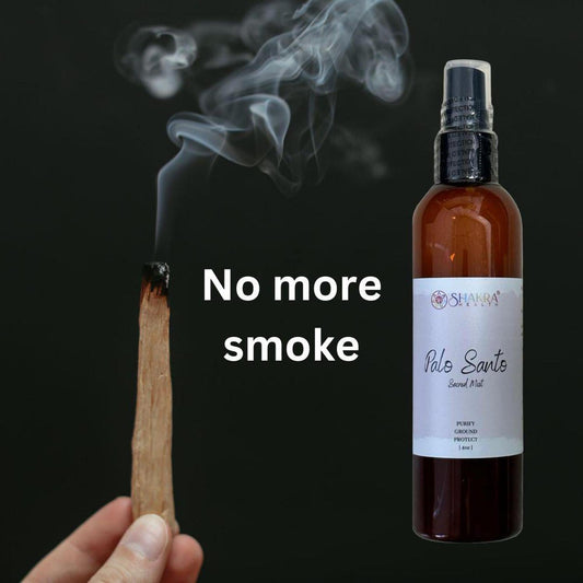 Amber spray bottle of Palo Santo Sacred Mist next to a smoking wood stick against a black background.
