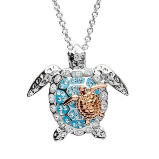 Sterling silver sea turtle necklace with blue crystals and a small rose gold baby turtle pendant on a silver chain.