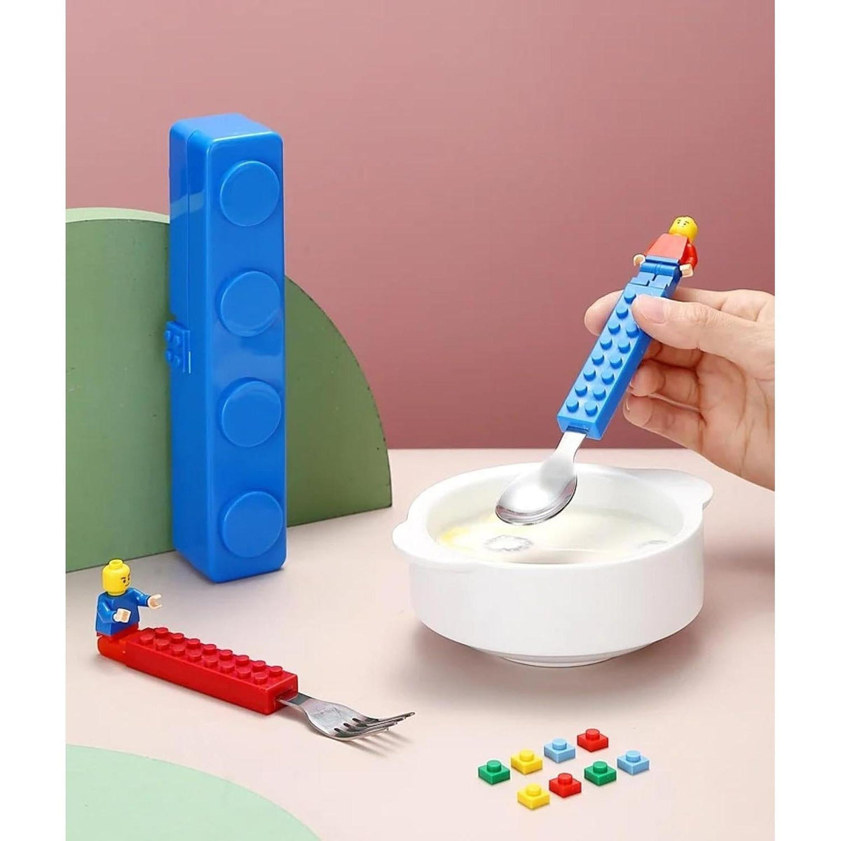 Blue and red building-block fork and spoon set with metal heads and a matching storage case on a table.