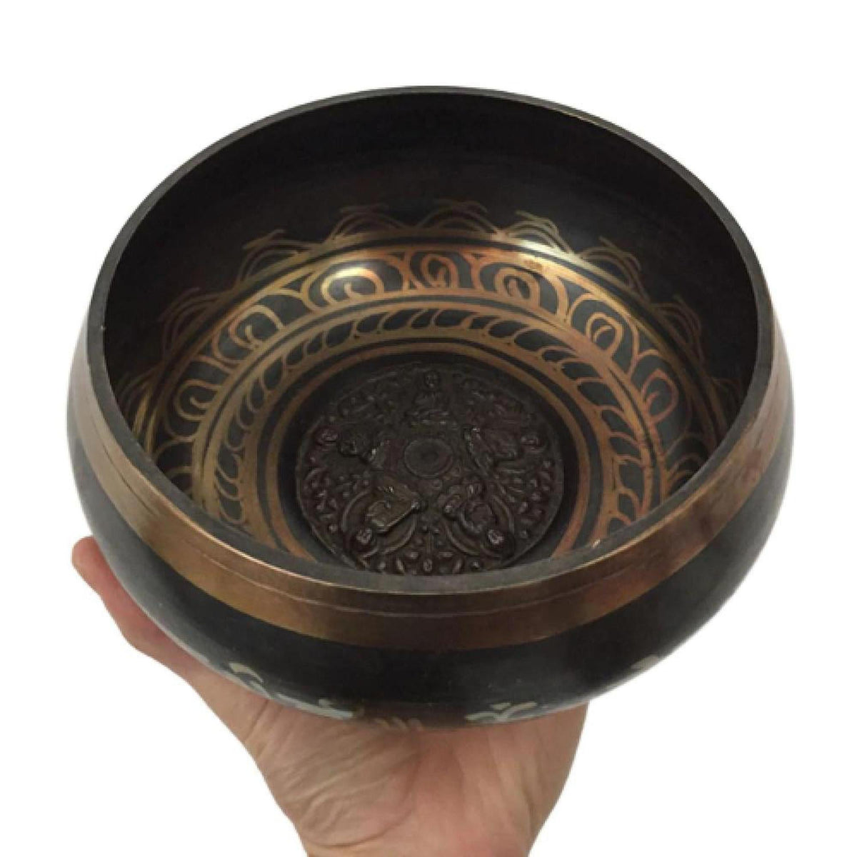 Handheld handcrafted copper Tibetan singing bowl with intricate gold-toned interior engravings and a dark rustic finish.