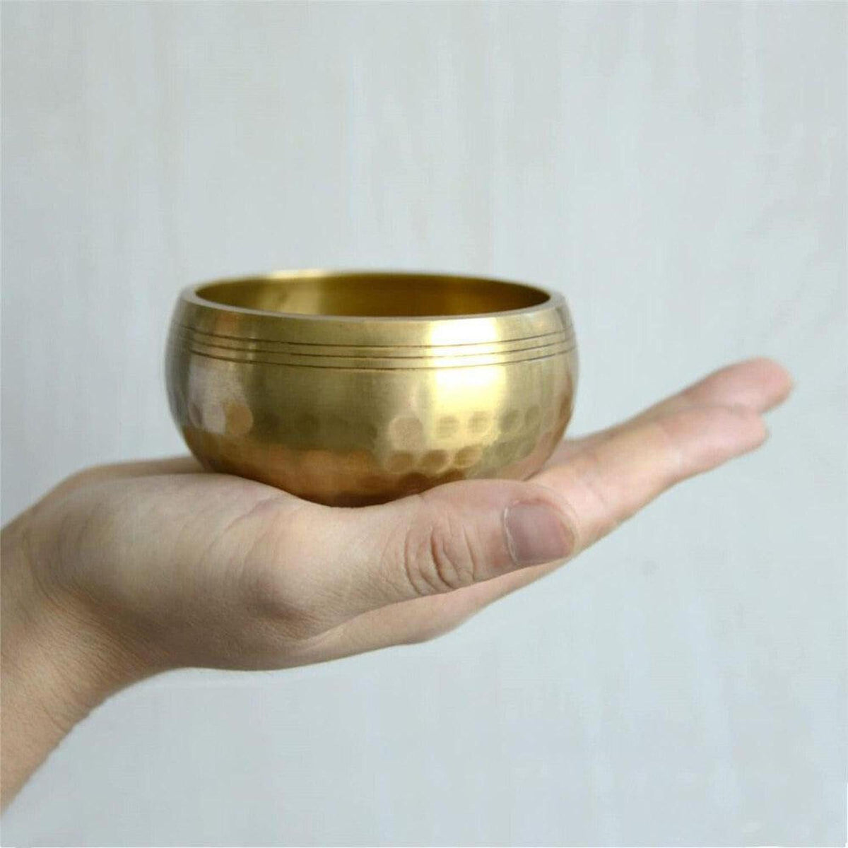 Handcrafted copper Tibetan singing bowl with a hammered finish held in a palm for meditation and sound healing.