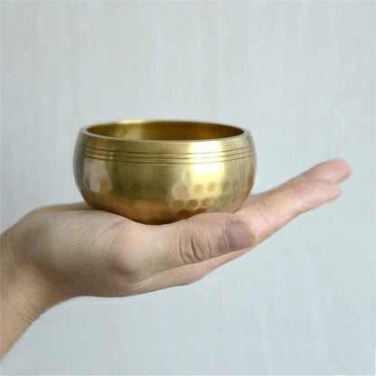 Handcrafted copper Tibetan singing bowl with a hammered finish held in a palm for meditation and sound healing.