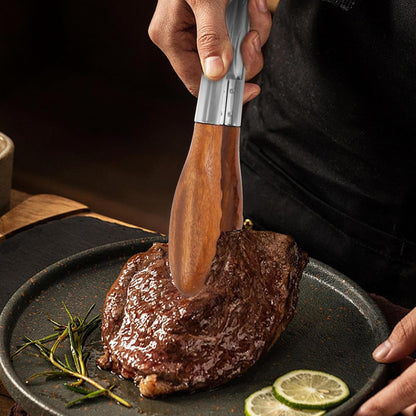 Stainless steel kitchen tongs with walnut wood heads gripping a cooked steak on a dark plate.
