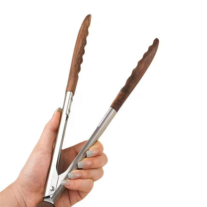 Hand holding kitchen tongs with stainless steel frames and natural walnut wood heads for non-stick cookware.